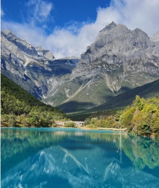 Blue Moon Valley's crystal-clear lake reflects the distant Jade Dragon Snow Mountain.