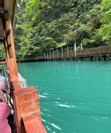 Tourists are sitting on the boat, surrounded by the crystal-clear blue water, with a stunning view all around.