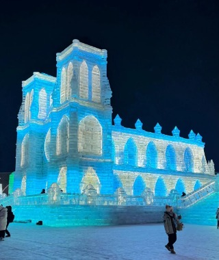 At night, the ice structures of the Harbin Ice and Snow Festival light up, vibrant and colorful.