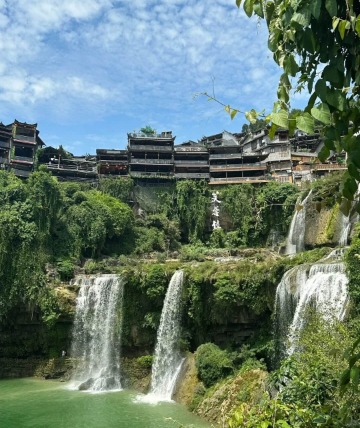 The sides of the waterfall are lined with lush trees.