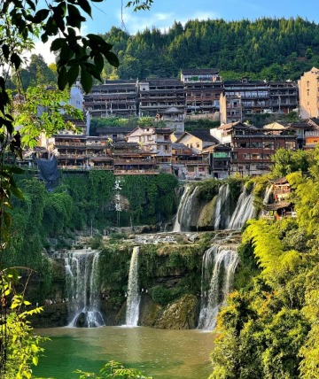 The grand waterfall of Furong Ancient Town during the daytime.