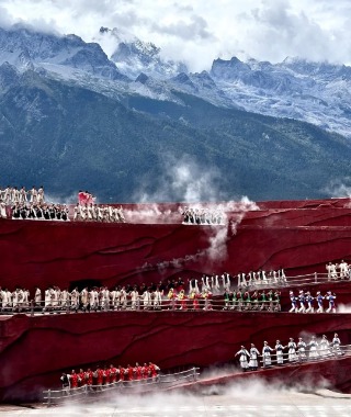 On stage, mist swirls around as performers dance in the rain and fog.