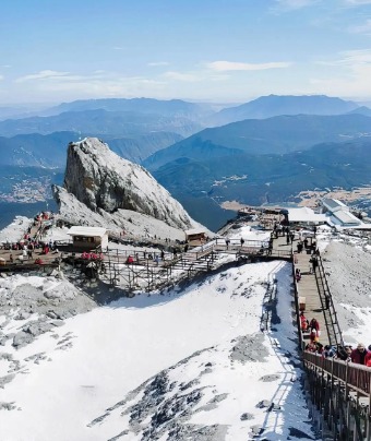 Tourists are climbing up Jade Dragon Snow Mountain along the wooden plank path.