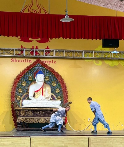 Two monks on stage are performing Chinese martial arts.