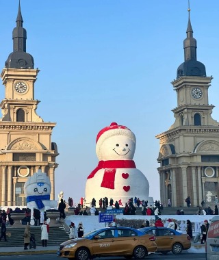 In Harbin, a giant snowman stands wrapped in a red scarf and wearing a red hat, surrounded by people taking photos.