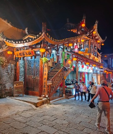 The stone-paved street lights up at night.