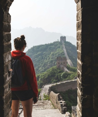 Tourists stand on a watchtower of the Great Wall, gazing into the distance.