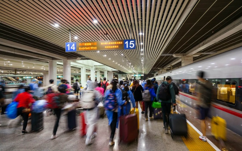 Tourists are carrying their luggage, getting ready to board the high-speed train.