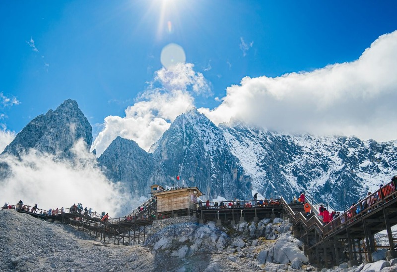 Tourists are hiking up Jade Dragon Snow Mountain on a wooden walkway. The weather's awesome.