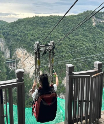 Tourists are experiencing the zip line in Zhangjiajie Grand Canyon.